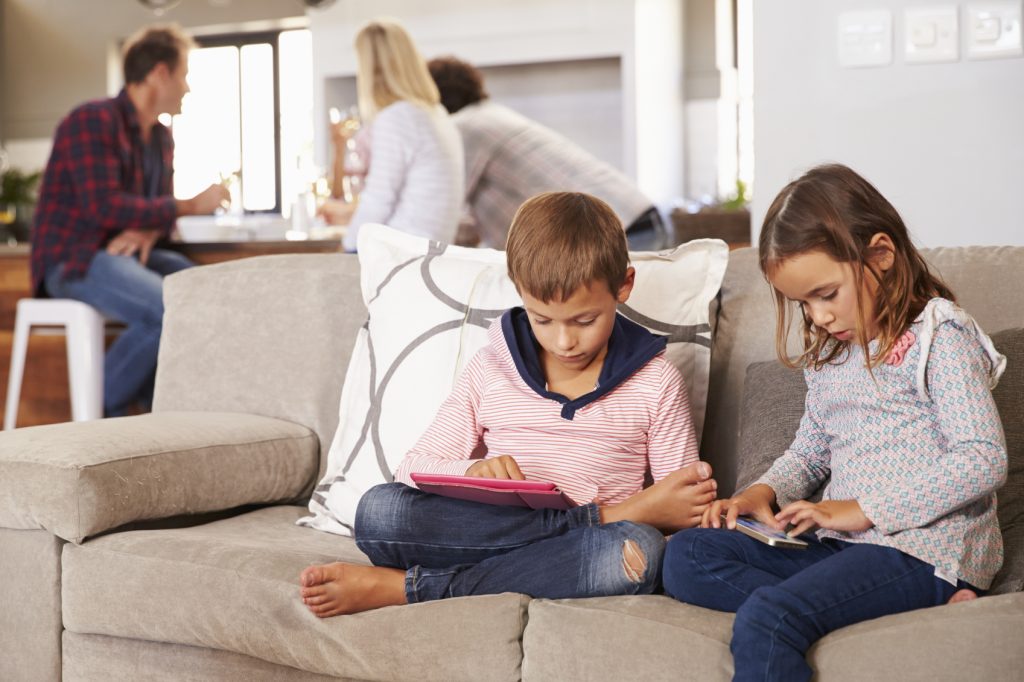 Kids playing with new technology while adults entertain