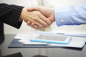 businessman and businesswoman are handshaking over documents and presentation